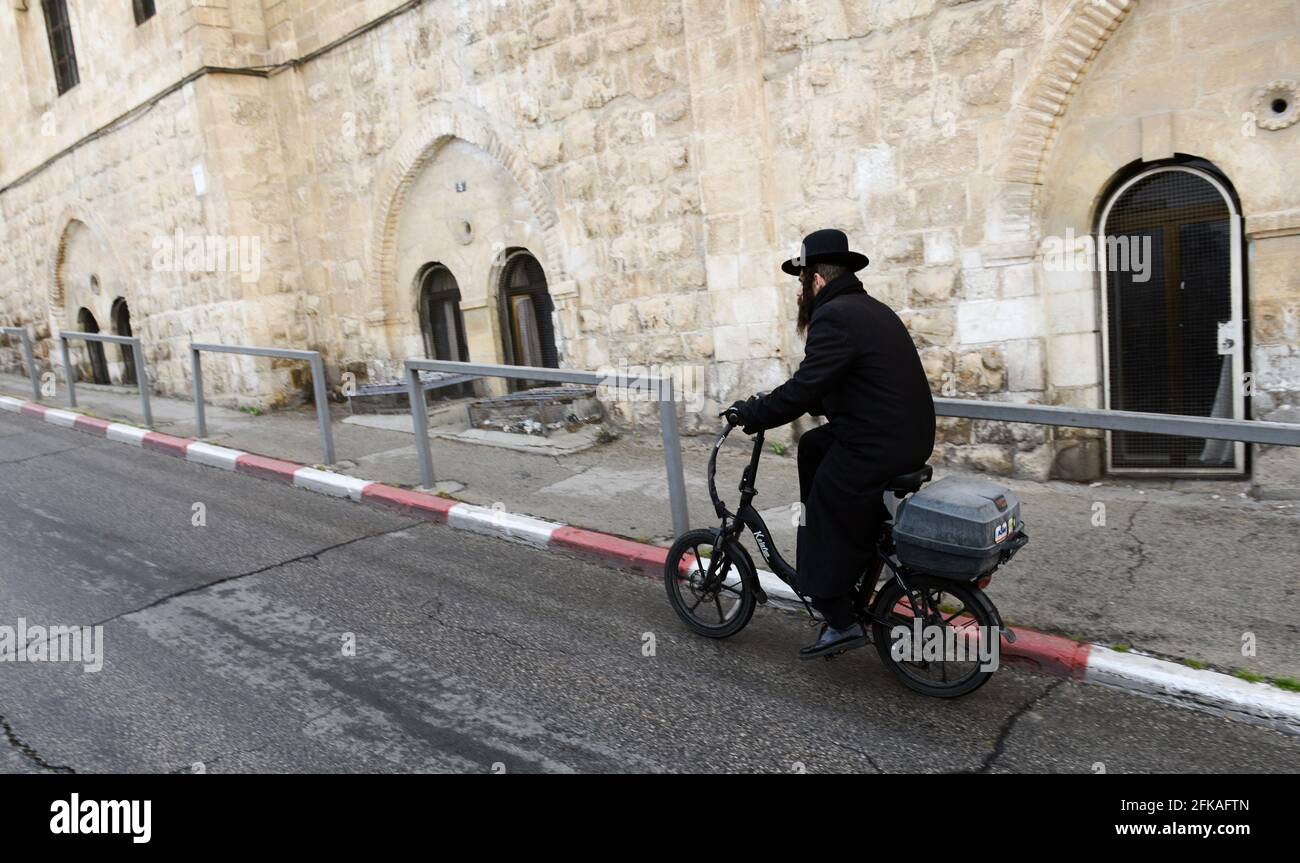 Un juif orthodoxe qui monte à vélo dans le quartier juif de la vieille ville de Jérusalem. Banque D'Images