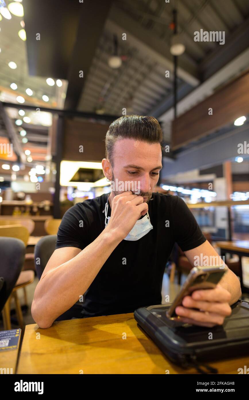 Homme assis au café tout en sociant et en utilisant prise de vue verticale du téléphone mobile Banque D'Images