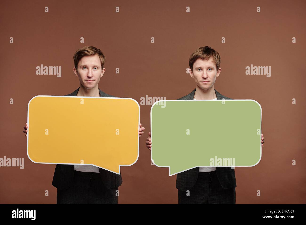 Portrait du contenu frères jumeaux debout sur fond marron et contient des étiquettes à bulles de parole colorées Banque D'Images