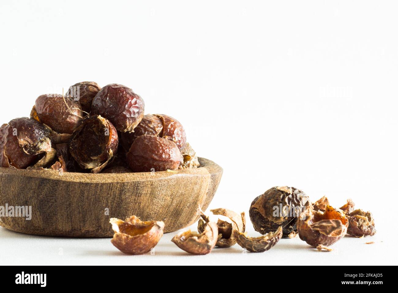 Noix de savon dans un bol en bois sur fond blanc; mode de vie écologique; durable; biologique Banque D'Images Noix de savon dans un bol en bois sur fond blanc; mode de vie écologique; durable; biologique Banque D'Images