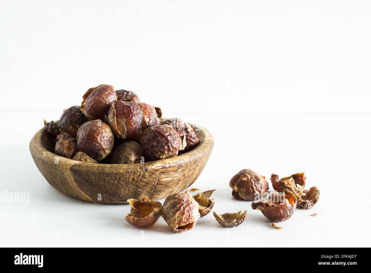 Noix de savon dans un bol en bois sur fond blanc; mode de vie écologique; durable; biologique Banque D'Images Noix de savon dans un bol en bois sur fond blanc; mode de vie écologique; durable; biologique Banque D'Images