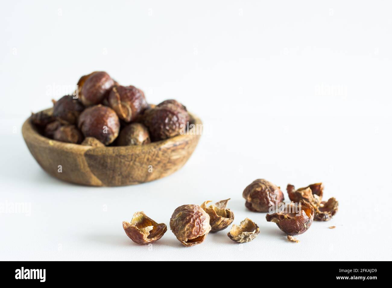 Noix de savon dans un bol en bois sur fond blanc; mode de vie écologique; durable; biologique Banque D'Images
