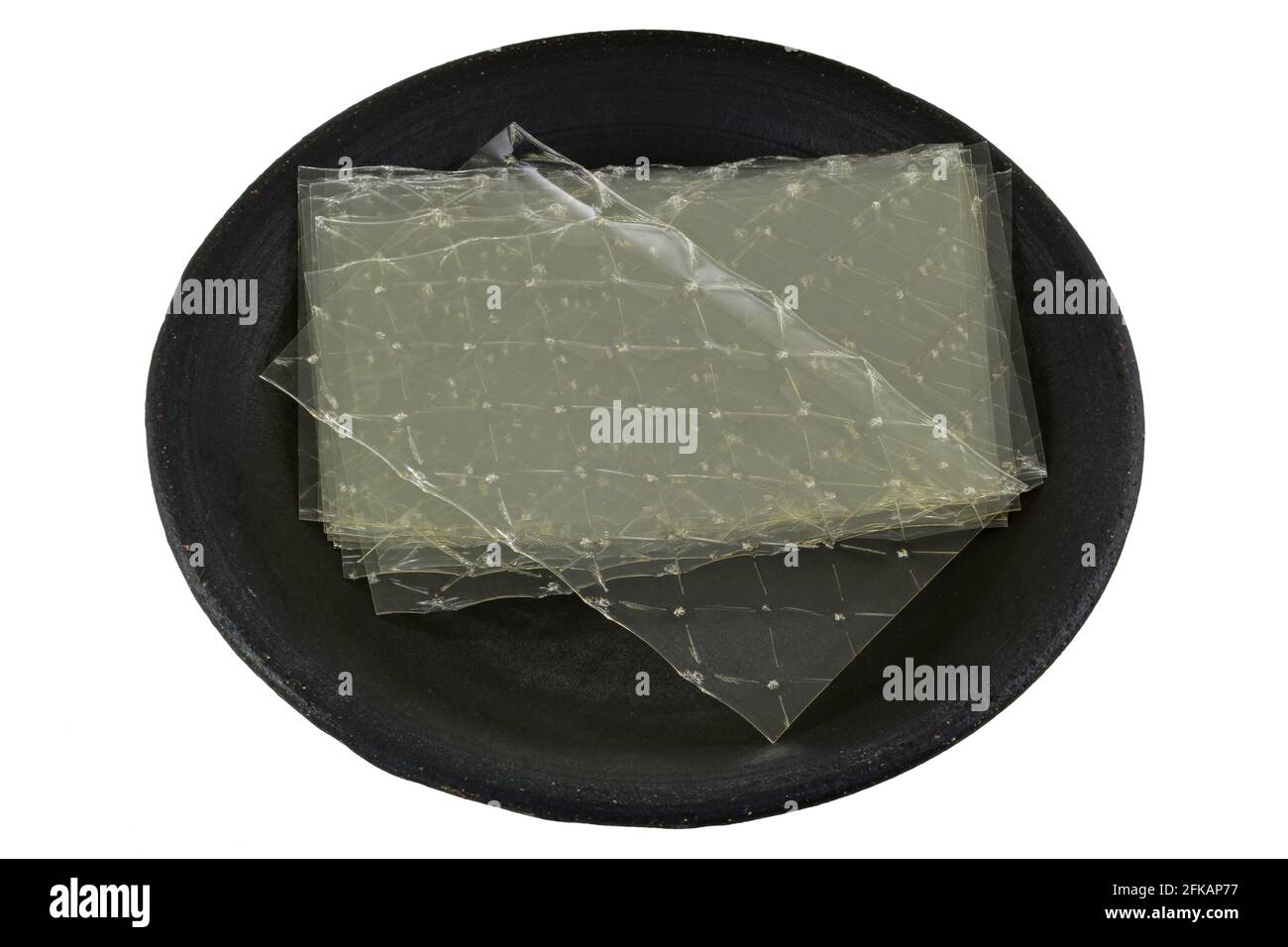 Feuilles de gélatine sur une plaque en céramique sombre, isolées sur du blanc Banque D'Images