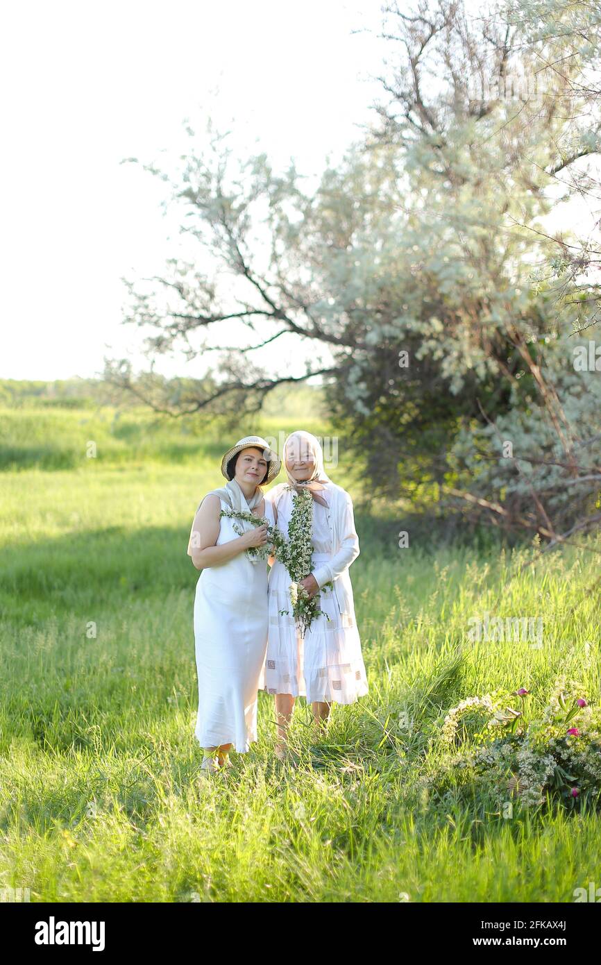 Portrait de granny avec fille marchant en plein air, portant des robes blanches. Banque D'Images