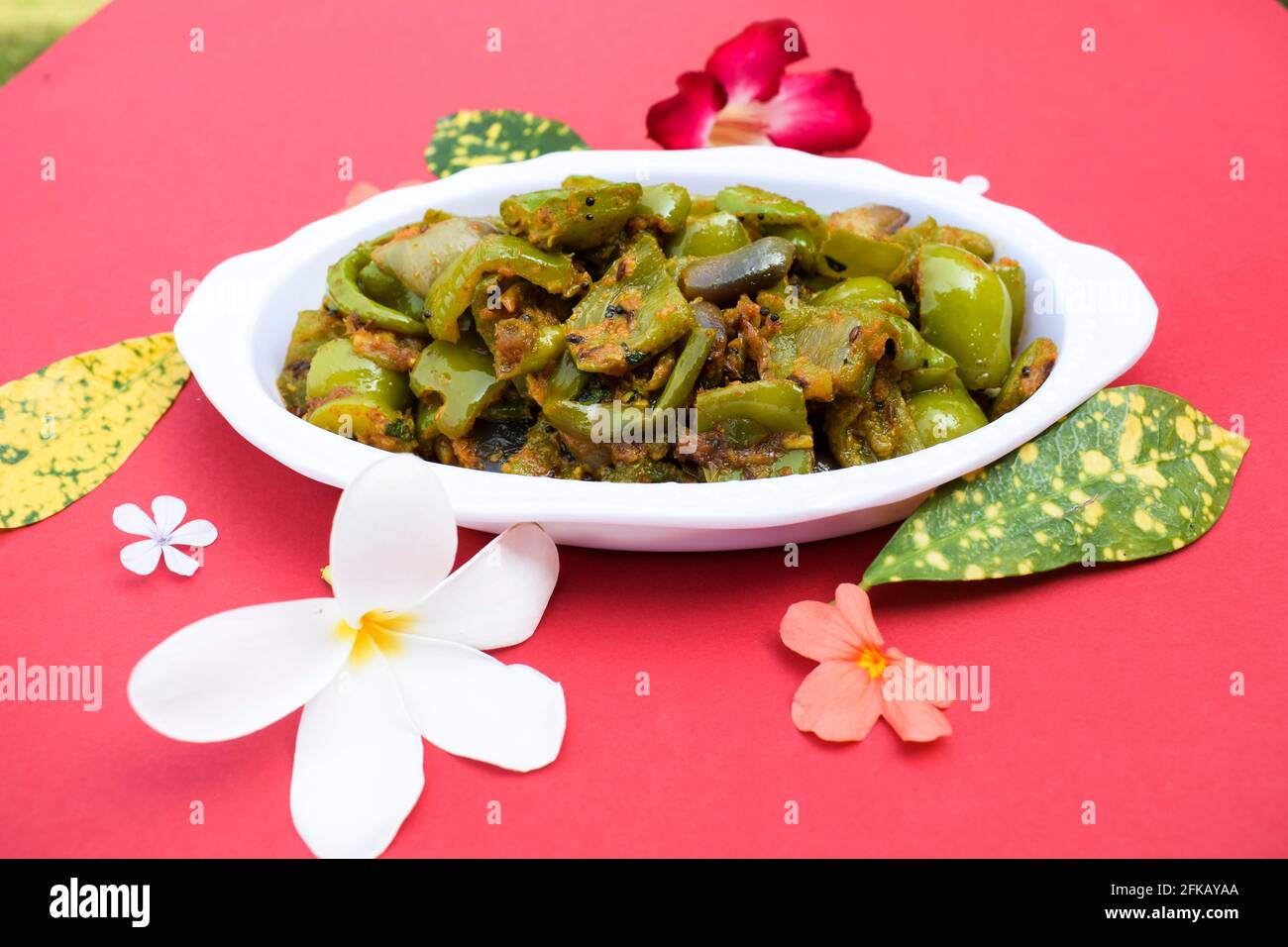 Délicieux cari au poivron vert ou au poivron vert. Remuez avec des oignons sautés sabaji asiatique indien avec du masala. Sur fond rouge, l'image de la nourriture est un espace de copie de Banque D'Images