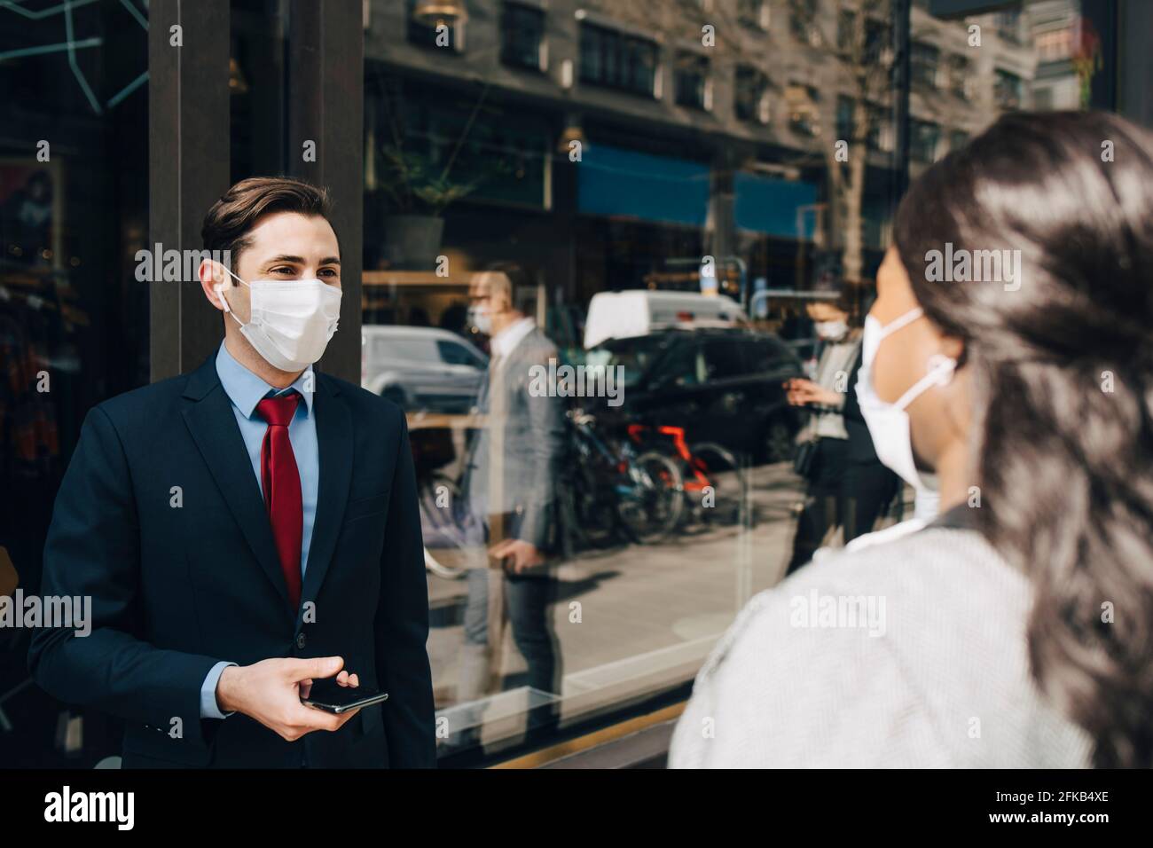 Homme d'affaires sous masque parlant avec une collègue pendant une pandémie Banque D'Images