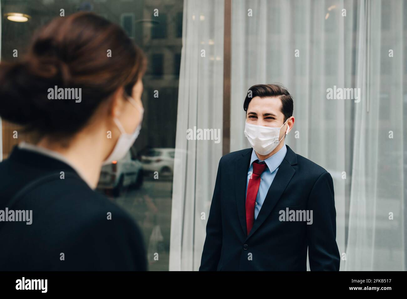 Homme d'affaires regardant une collègue féminine à l'extérieur du magasin pendant une pandémie Banque D'Images