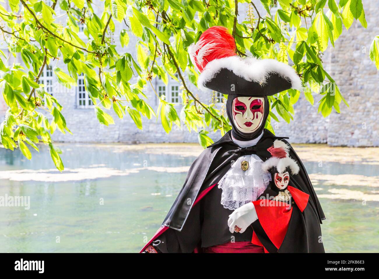 Costume vénitien noir portant une figurine à l'image de le masque crème Banque D'Images