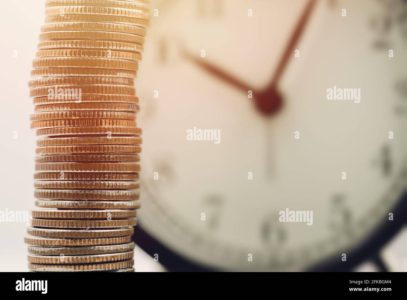 pièce d'argent empilée sur l'arrière-plan des heures d'horloge, le concept de temps d'affaires de richesse avec heures de travail Banque D'Images