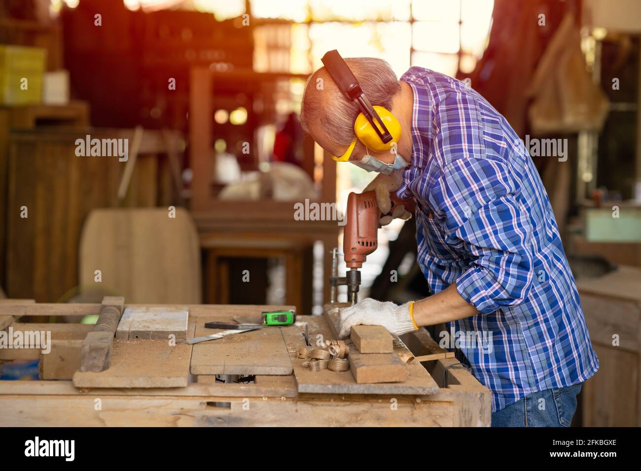 Travailleur aîné bois woodcraft retraite hobby pour la bonne retraite, asiatique homme mature maître professionnel de la fabrication de meubles en bois avec masque protecteur Banque D'Images