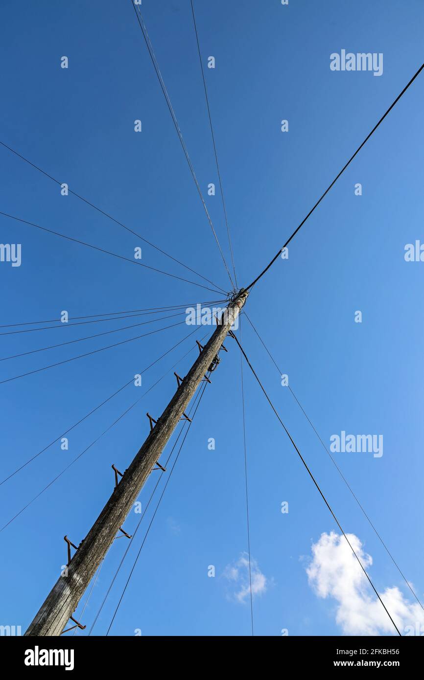 Un mât téléphonique ancien entouré d'une toile de lignes téléphoniques aériennes menant aux foyers des clients Banque D'Images