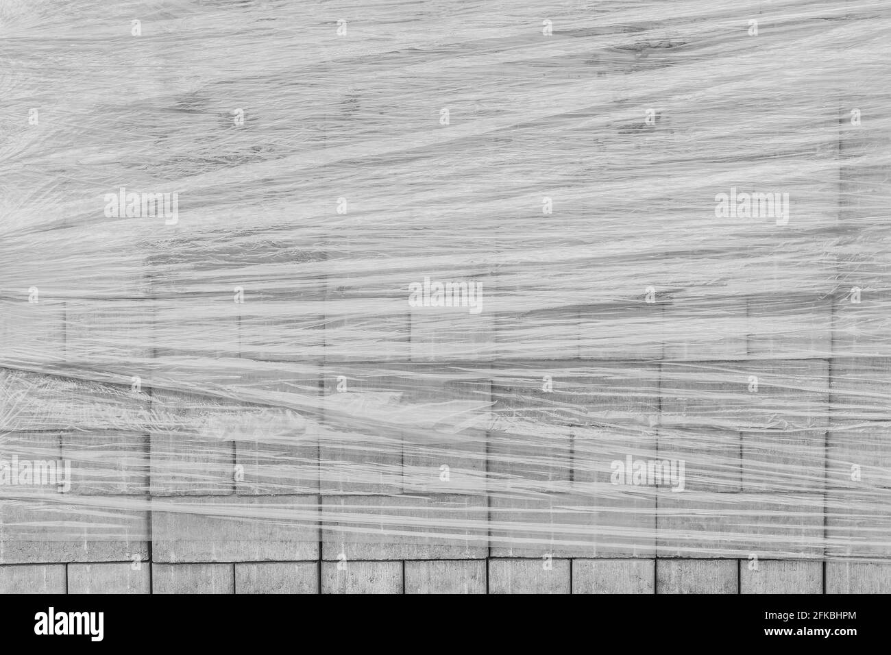 Une pile de nouvelles dalles de pierre de pavage enveloppées d'un film plastique. Matériaux de construction de carreaux sur le chantier. Banque D'Images