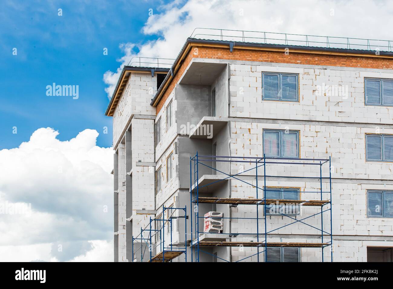 Façade blanche ciplicate blocs matériau d'une nouvelle maison urbaine moderne inachevée sur un chantier de construction contre un ciel bleu avec des nuages. Banque D'Images