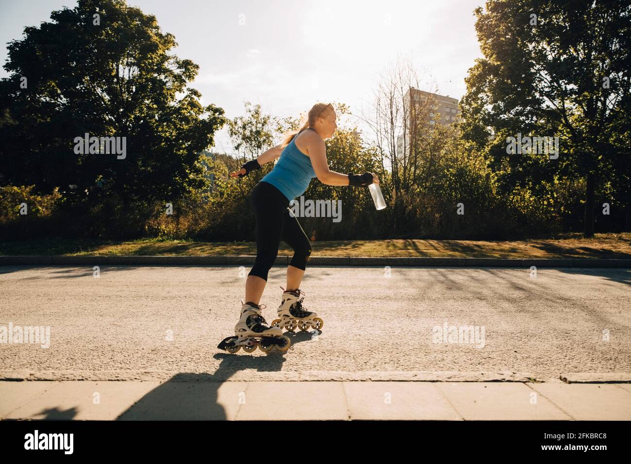 Athlète féminine patinage à roulettes dans la rue pendant la journée ensoleillée Banque D'Images