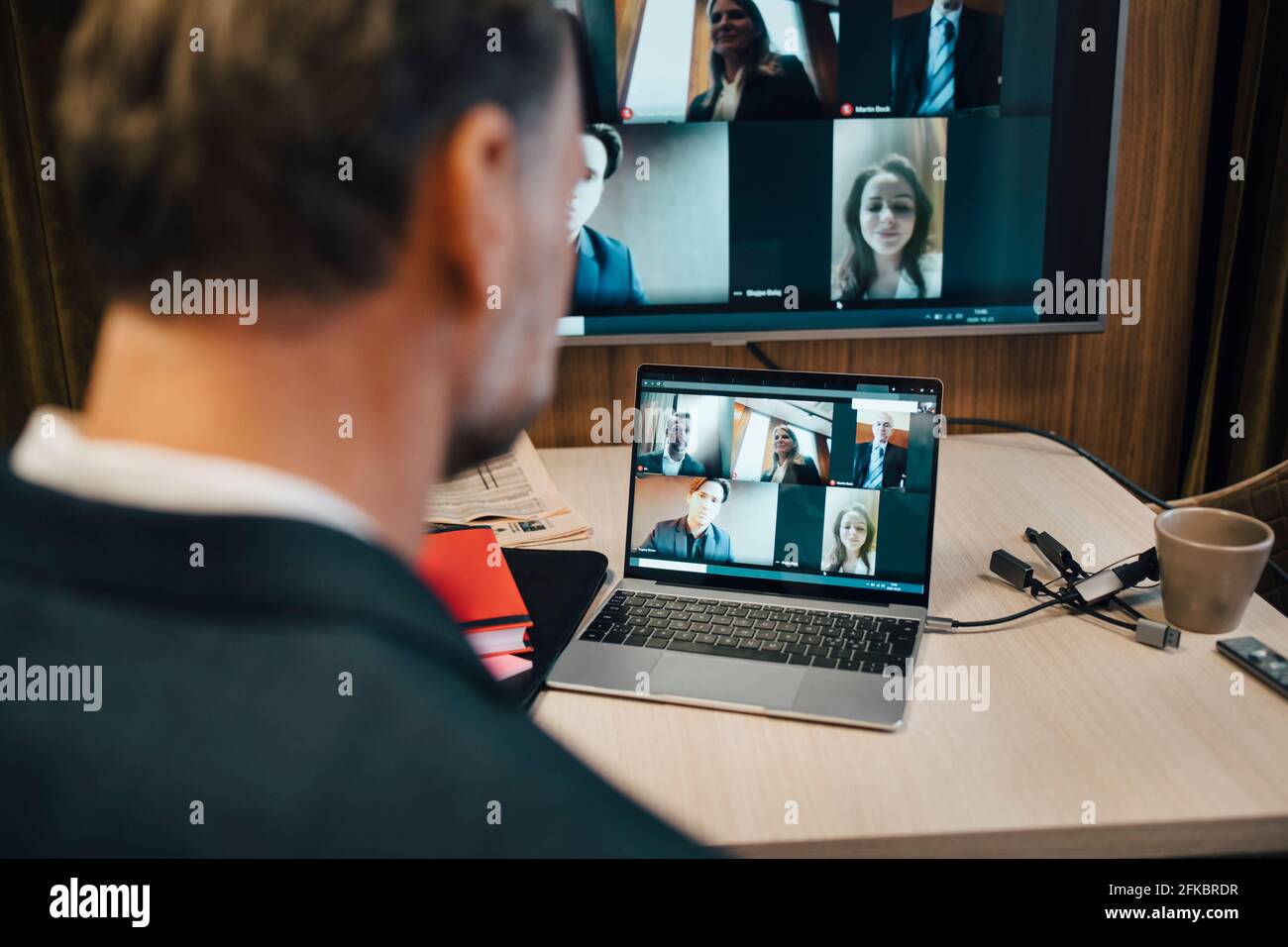 Homme d'affaires discutant avec des collègues par vidéoconférence pendant la prise de distance sociale au bureau Banque D'Images