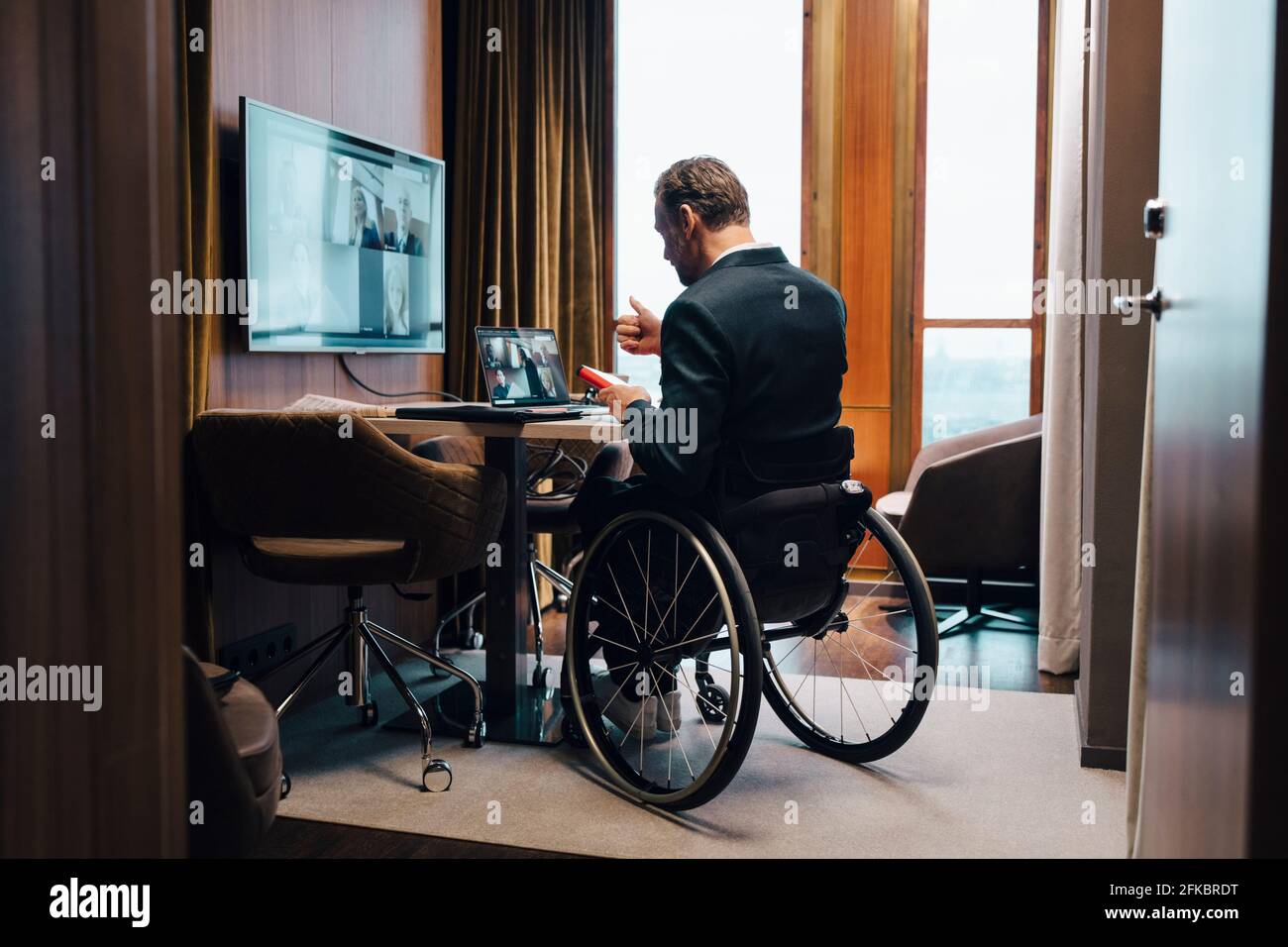 Homme d'affaires handicapé avec des collègues en vidéoconférence au bureau pendant pandémie Banque D'Images
