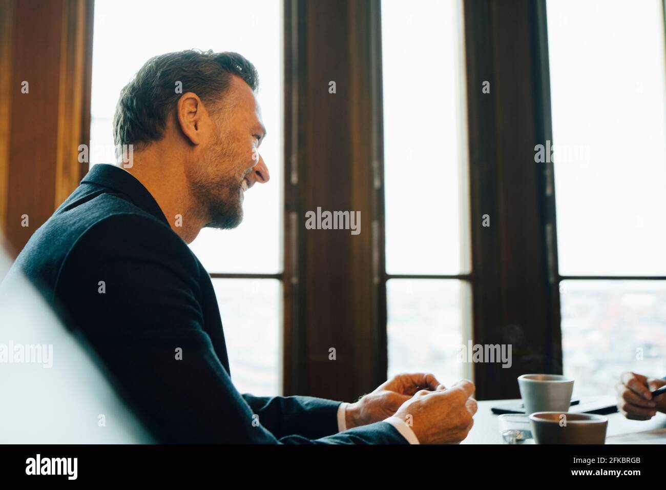 Homme entrepreneur souriant en discussion avec un collègue au bureau Banque D'Images