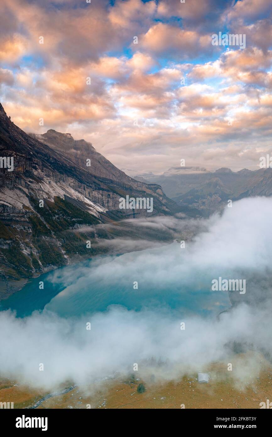 Nuages au coucher du soleil sur le lac immaculé Oeschinensee dans la brume, Oberland bernois, Kandersteg, canton de Berne, Suisse, Europe Banque D'Images