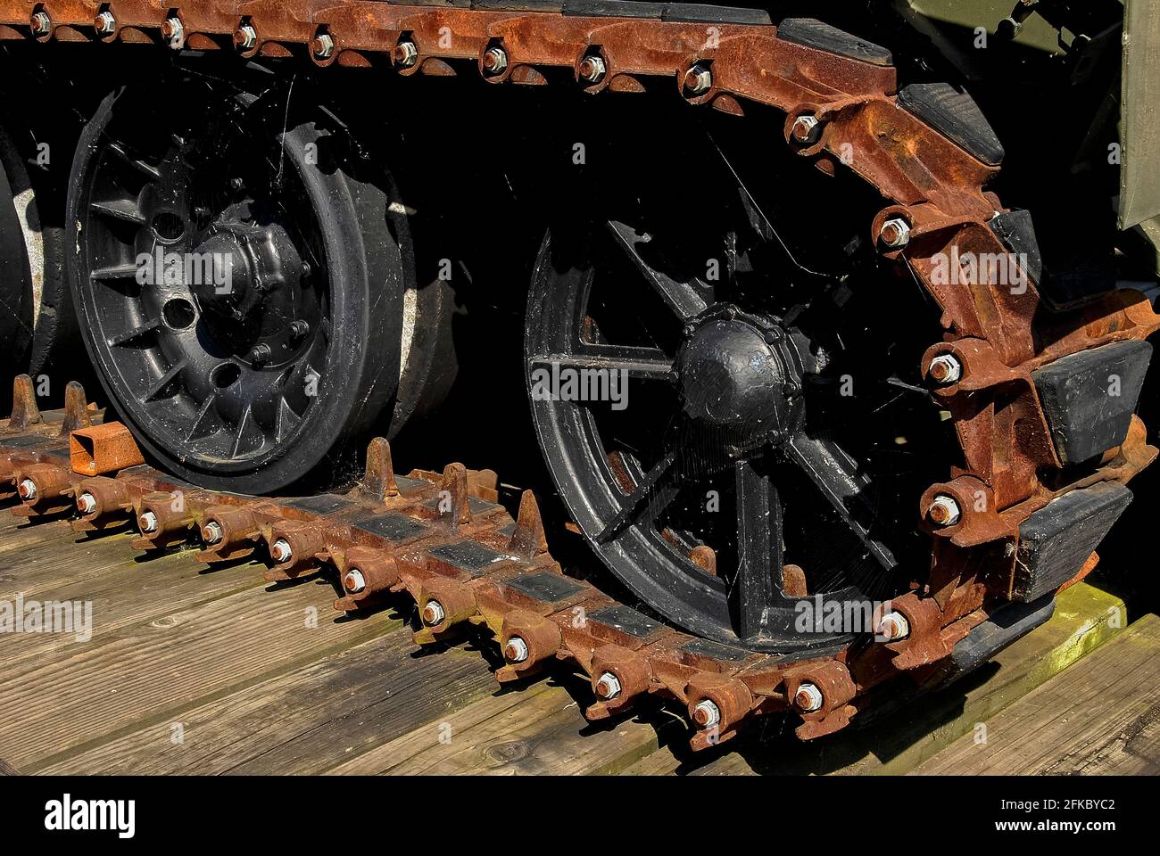 Les toiles d'araignée sont baignées de lumière intense contre les roues peintes en noir et la piste rouillée en caoutchouc d'un tracteur cet (combat Engineer Tractor) FV180 de l'armée britannique, un engin de terrassement amphibie ou bulldozer blindé de 17.5 tonnes construit pour éliminer les obstacles, creuser des fosses, préparer des barrières et sauver des véhicules échoués. Il a servi en Irak pendant la première Guerre du Golfe de 1991 et est maintenant exposé avec d'autres équipements militaires à Monmouth, Monbucshire, pays de Galles, Royaume-Uni, devant la Great Castle House, le quartier général et le musée régimentaire des Royal Monbucshire Royal Engineers (Milice). Banque D'Images