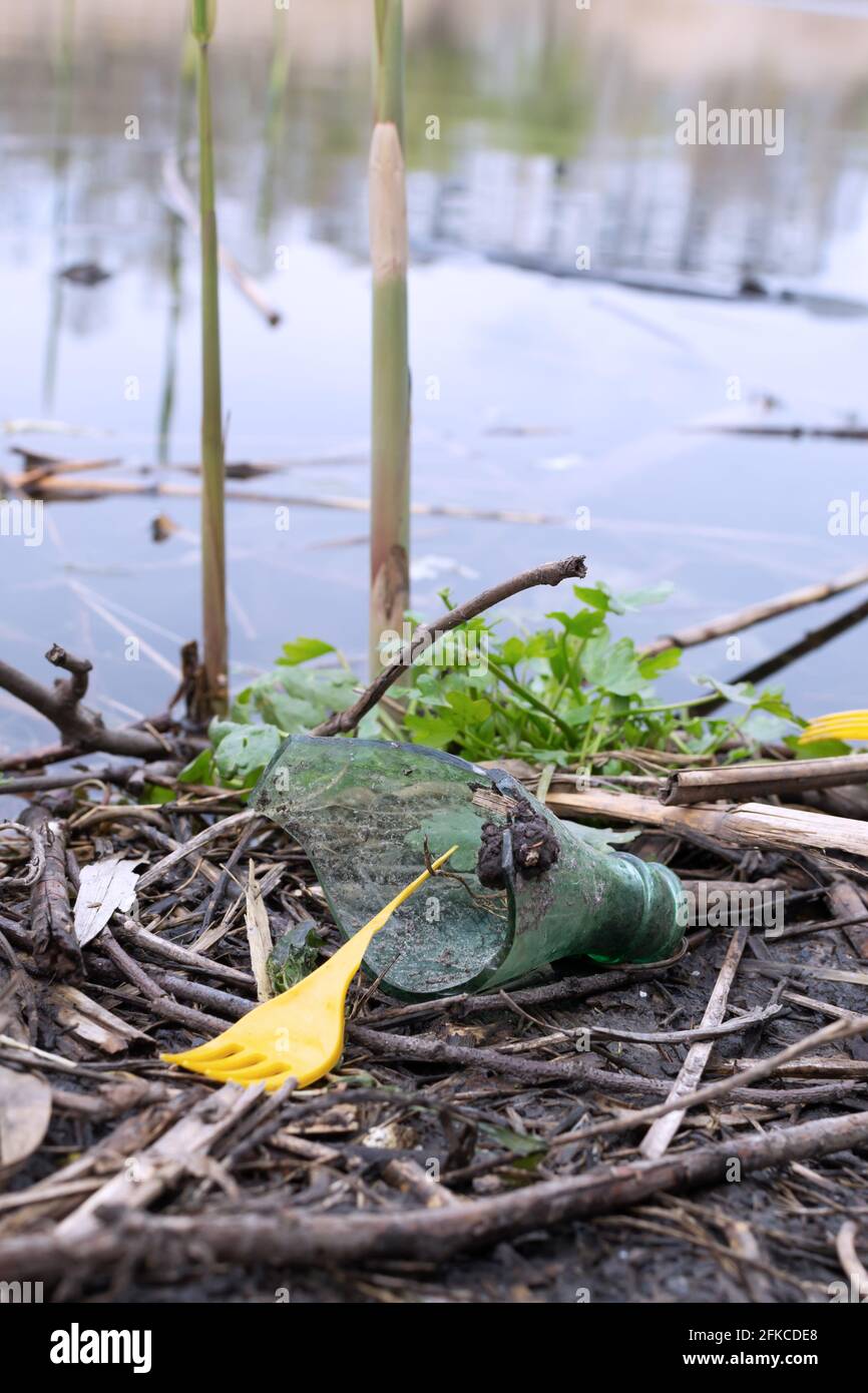Bouteille de verre cassée et wiccas de plastique cassé sur la rive. Concept de pollution de la planète. Banque D'Images
