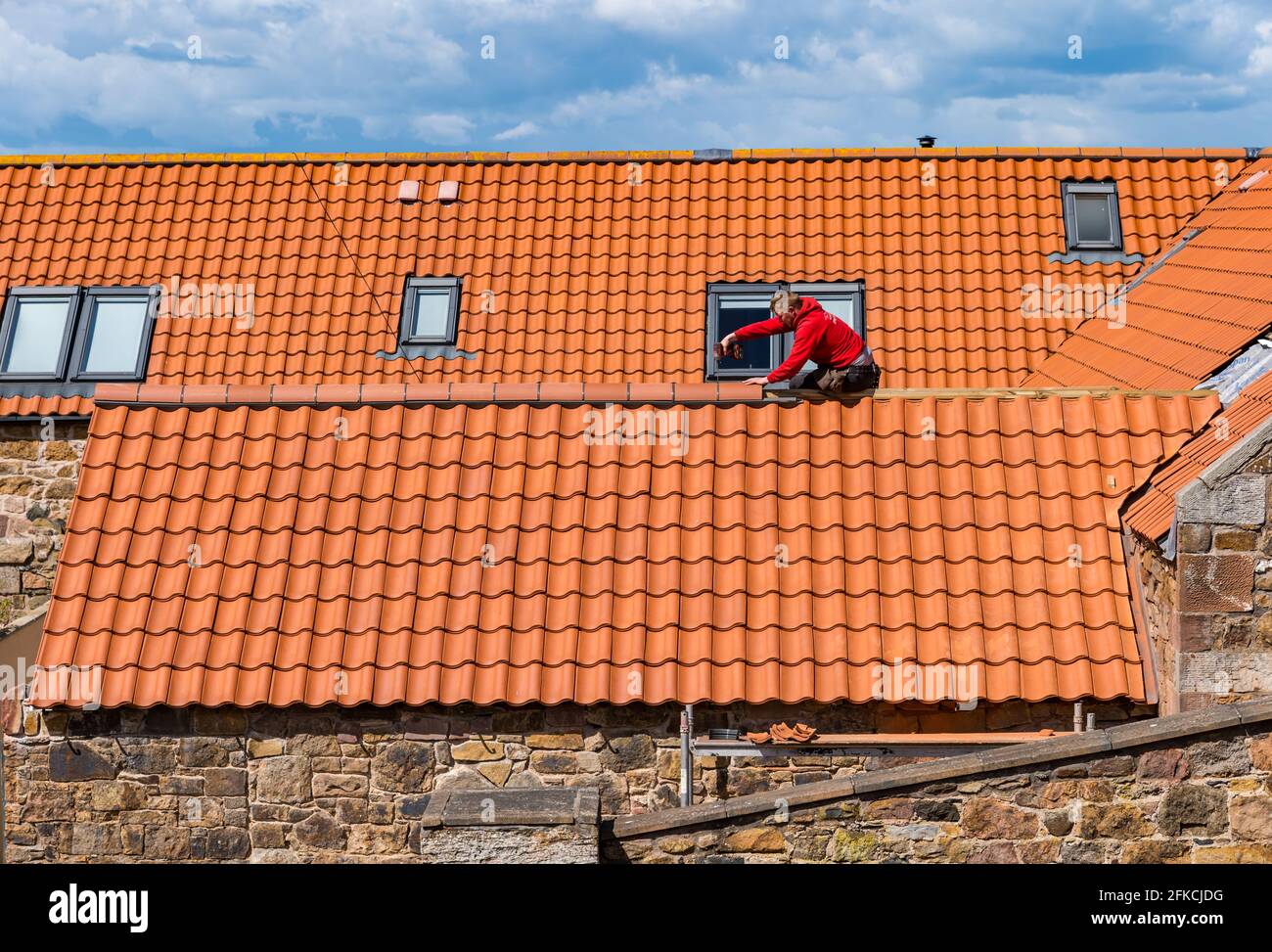 Couvreur de Workman posant des tuiles rouges sur le toit de l'ancienne ferme de rénovation de maison, East Lothian, Écosse, Royaume-Uni Banque D'Images