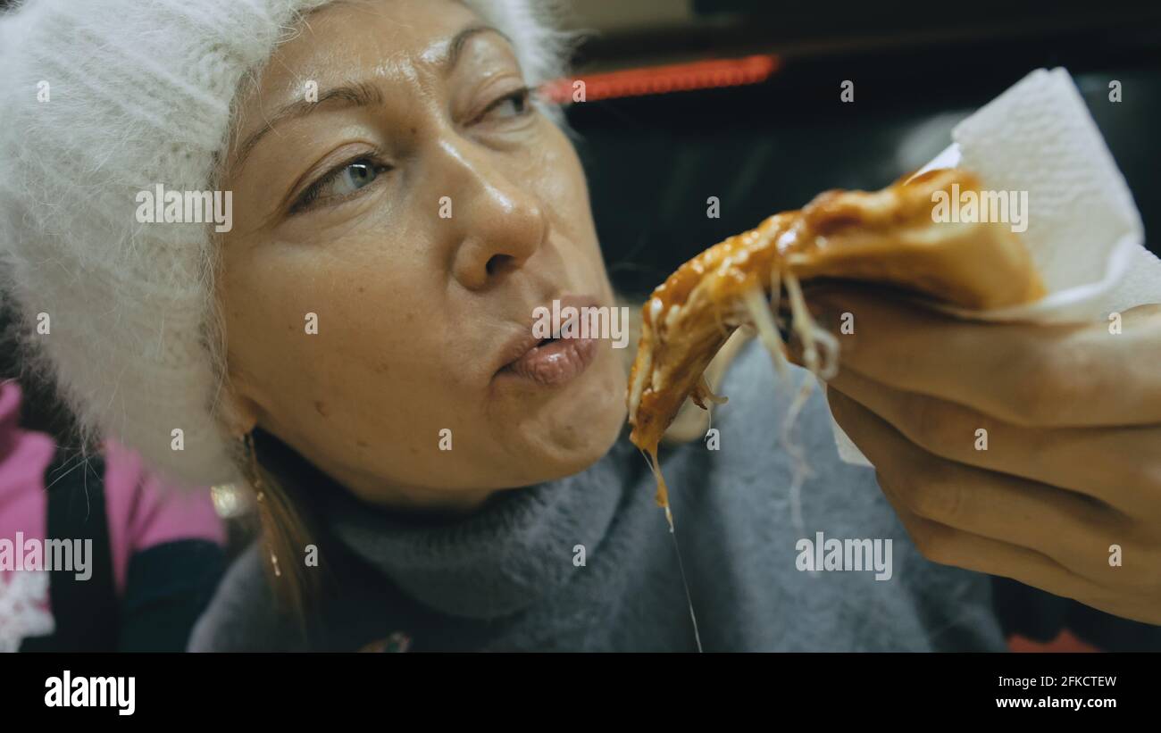 Fille manger du fromage à pizza quatre. Gros plan sur la bouche de la jeune femme manger de la pizza et mâcher dans le restaurant extérieur. De la nourriture indésirable. Pizza à partir de la boîte ouverte. Banque D'Images