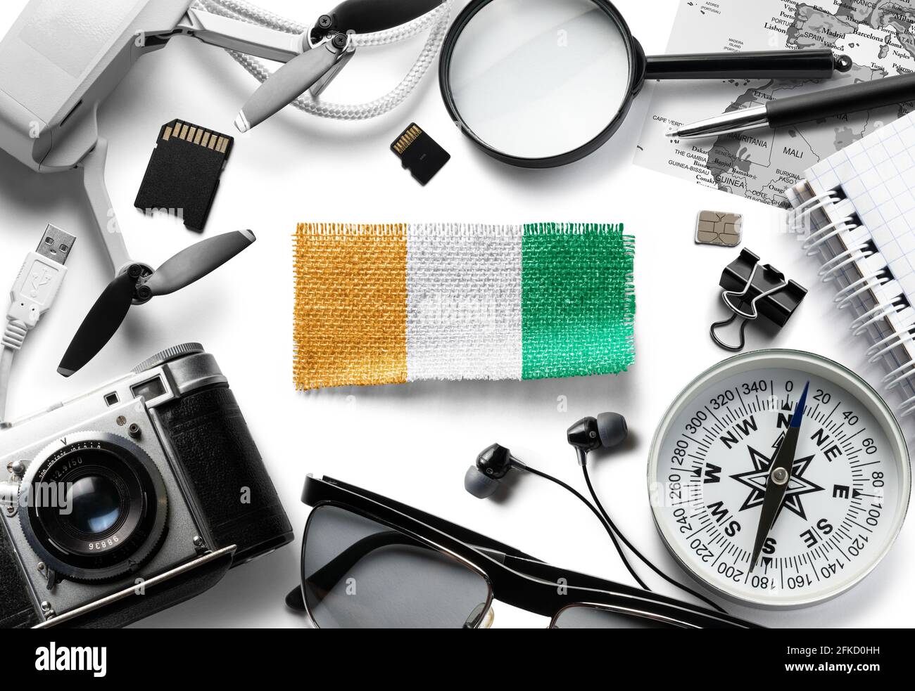 Drapeau de la Côte d'Ivoire et accessoires de voyage sur fond blanc. Banque D'Images