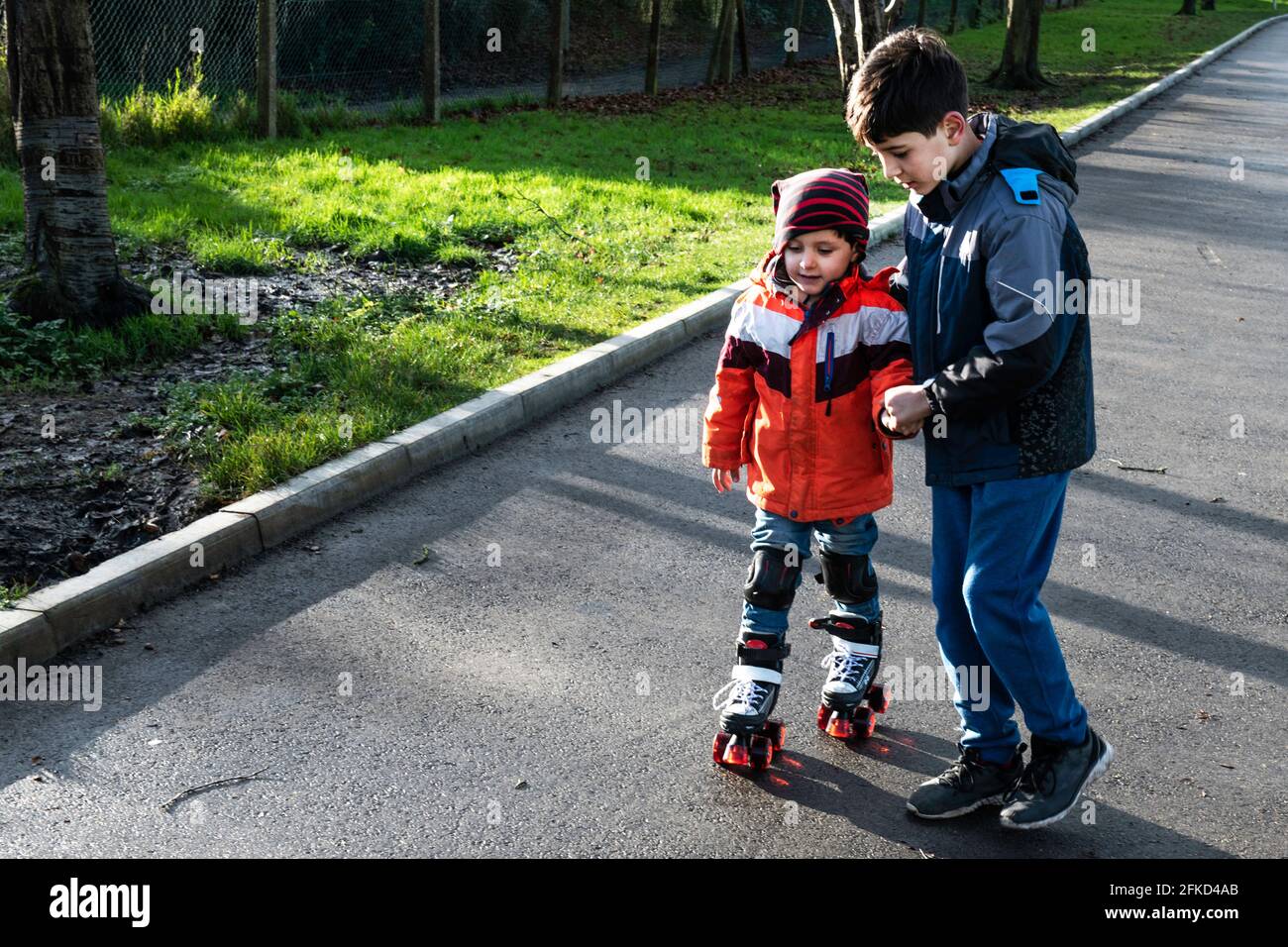 Royaume-Uni, frère de soutien de garçon avec patins à roulettes Banque D'Images