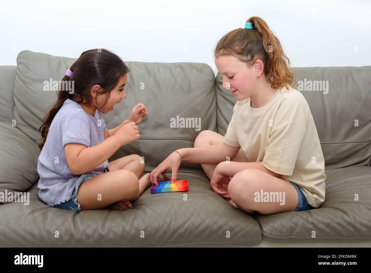 Deux enfants adorables jouant avec le violon Pop IT. Une fille riante lève les mains dans la victoire. Pousser pop bulle flexible violon jouet sensoriel fournir décharge et sont bons pour le développement de l'enfant. Banque D'Images