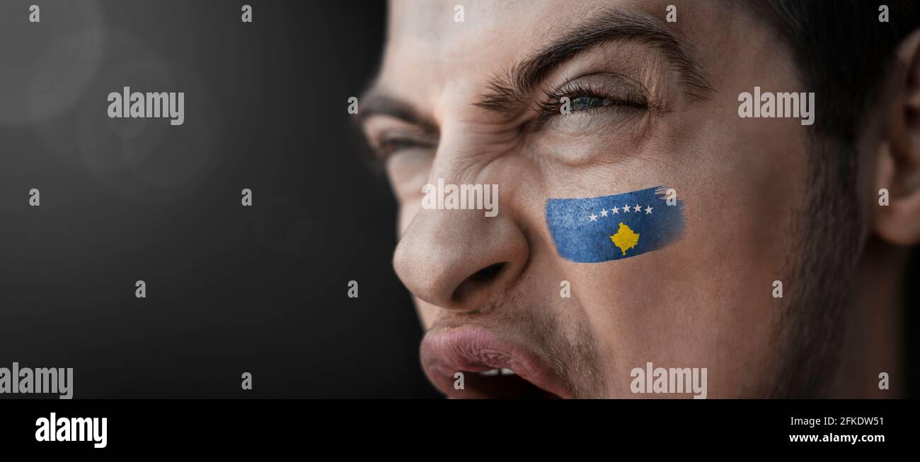 Un homme hurlant avec l'image du drapeau national du Kosovo sur son visage Banque D'Images