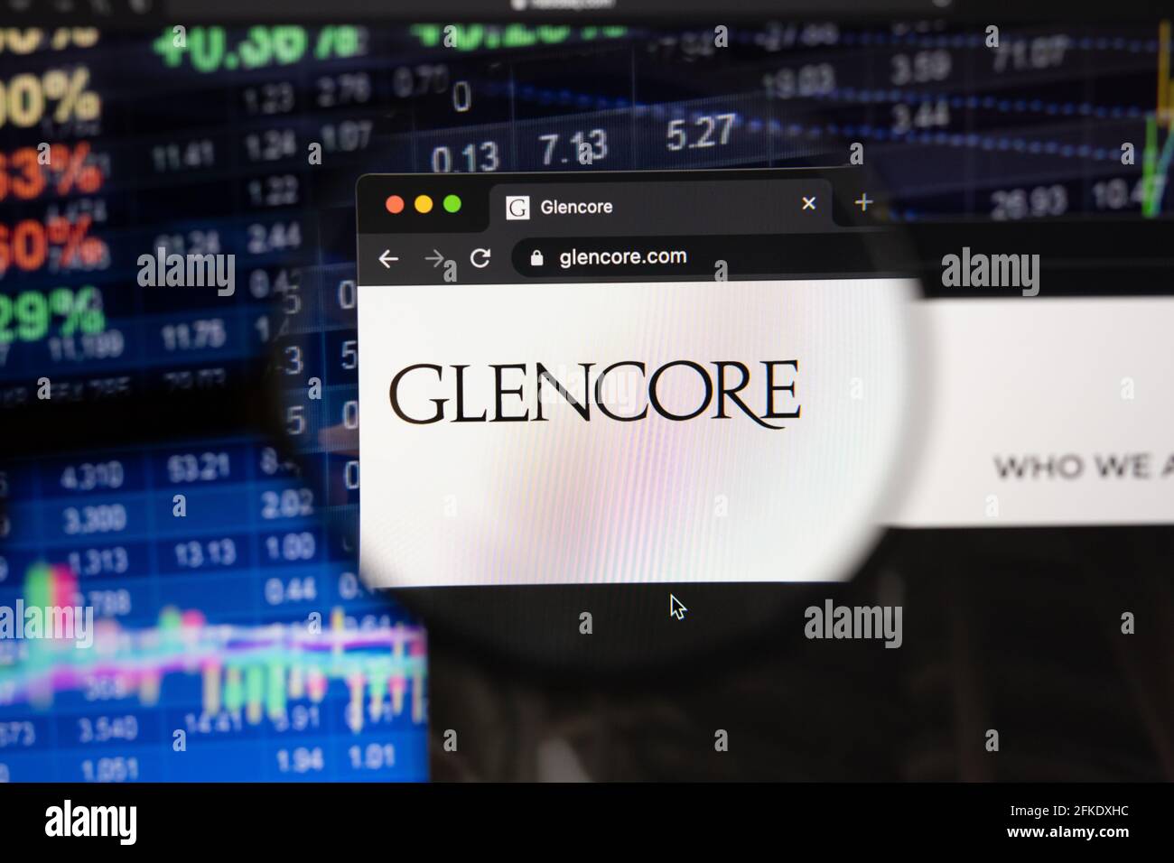 Le logo de la société Glencore sur un site Web avec des développements flous de marché boursier en arrière-plan, vu sur un écran d'ordinateur à travers une loupe Banque D'Images