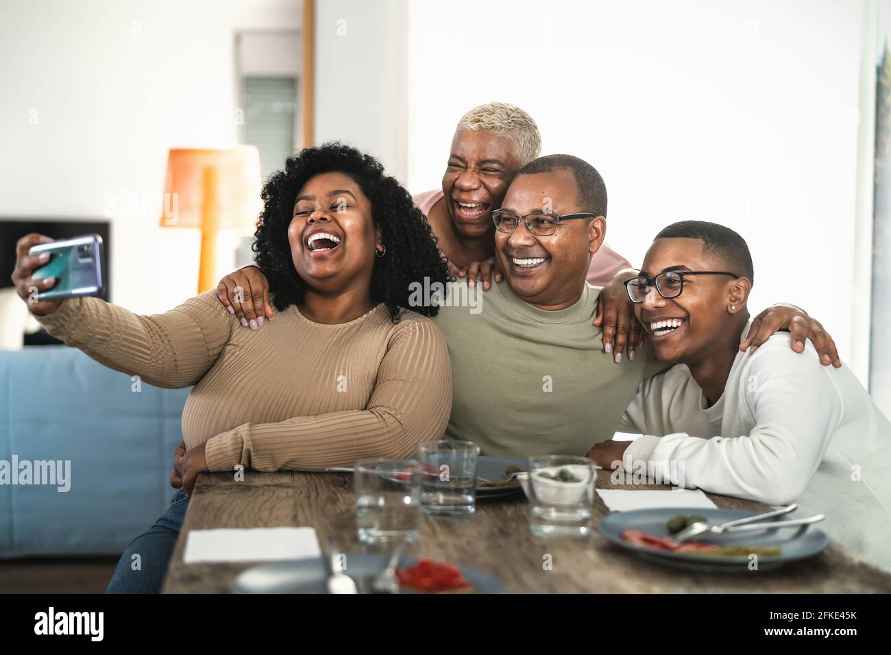 Bonne famille noire s'amusant à prendre un selfie avec un smartphone mobile cam tout en déjeunant à la maison Banque D'Images