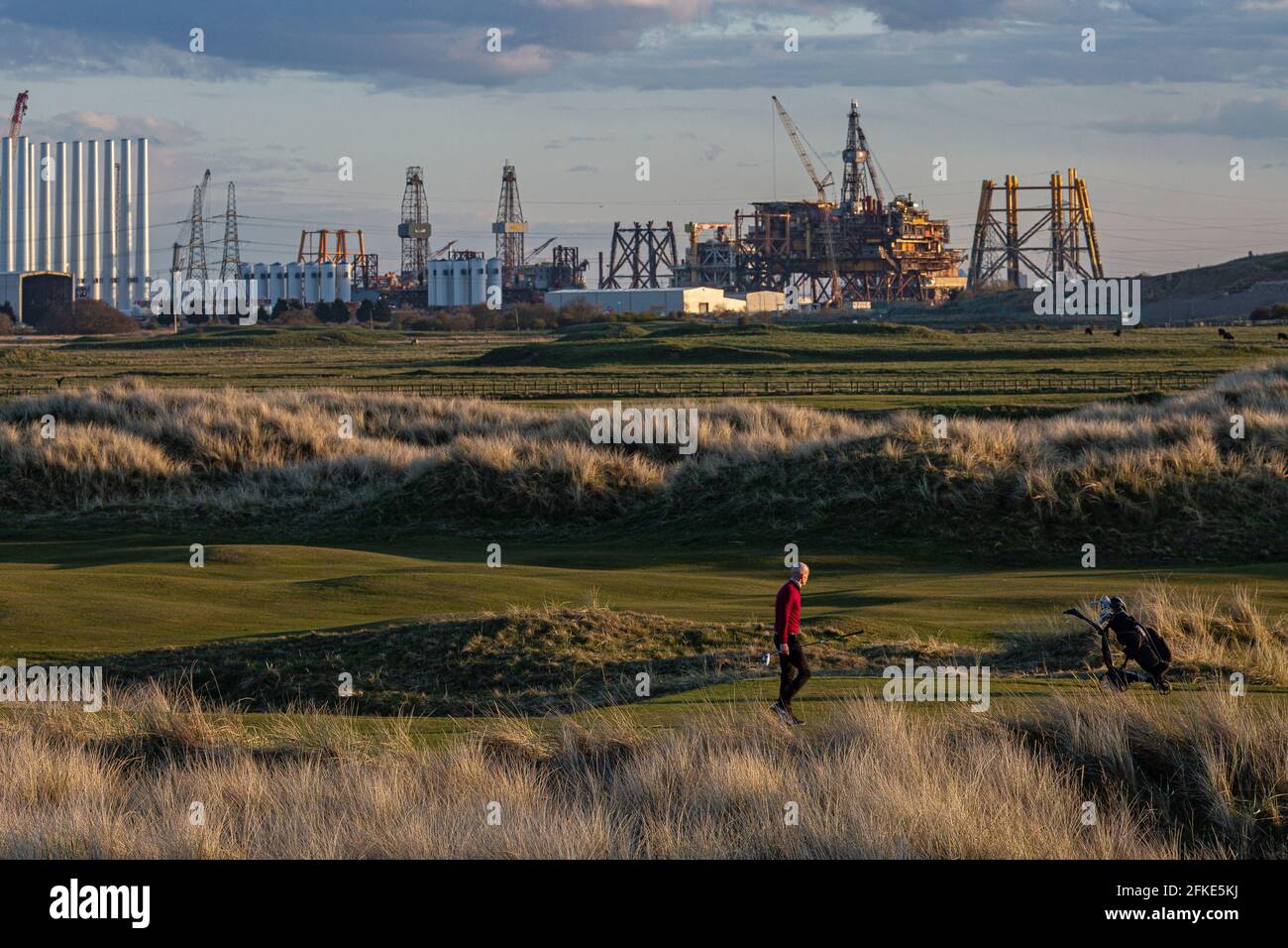Joueur de golf jouant au Seaton Carew Golf Club avec le Plate-forme offshore Shell Brant en cours de démontage et Recyclé à distance Banque D'Images
