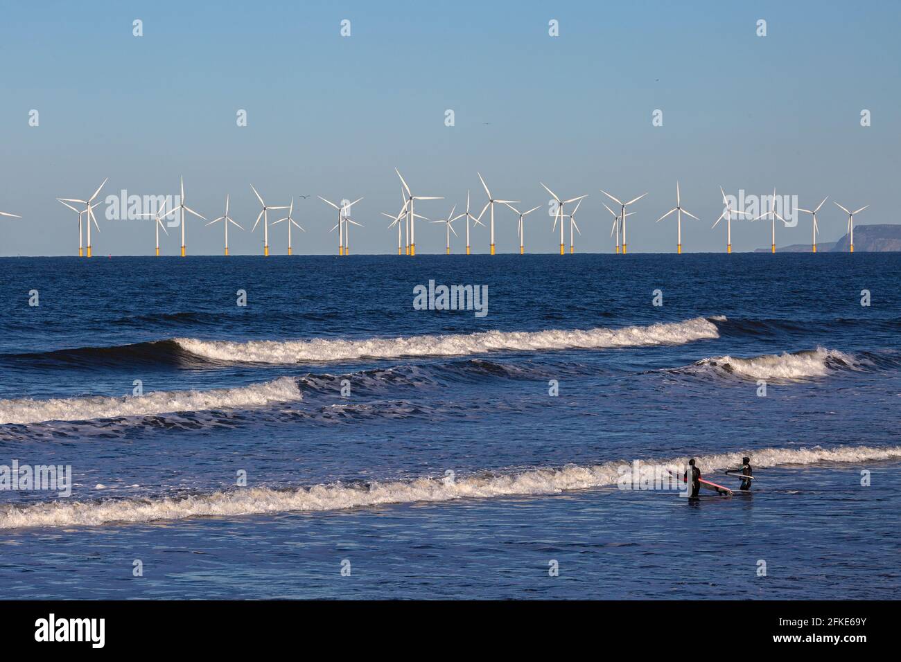 Olivia Harris (à droite) et son amie Rachel surfant à Seaton avec Teesside Offshore Windfarm à distance. Angleterre, Royaume-Uni Banque D'Images