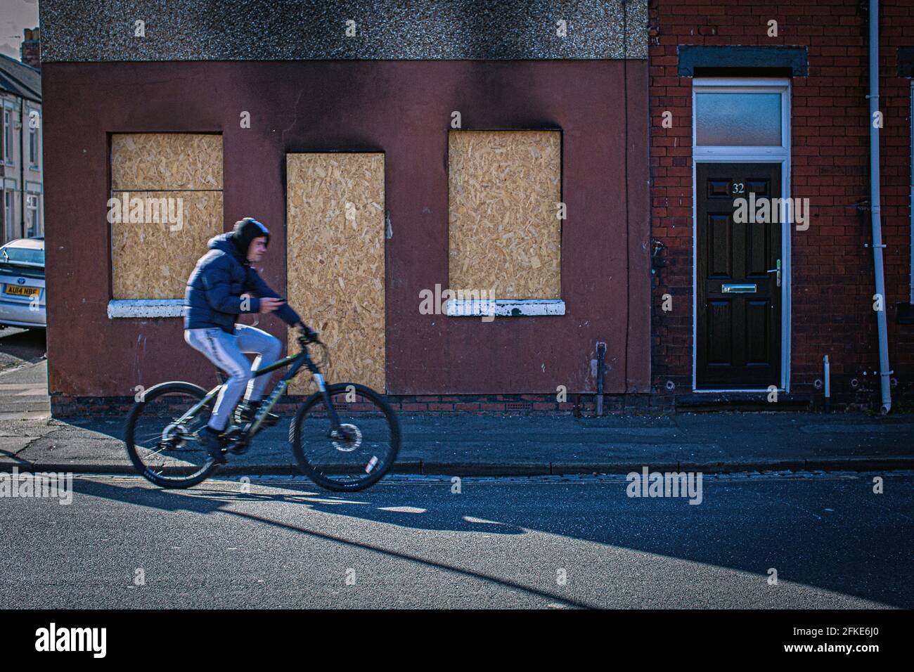 Homme en vélo passant a embarqué des fenêtres et des portes dans les rues les plus privées, qui sont autour du centre-ville de Hartlepool, comté de Durham, Royaume-Uni Banque D'Images