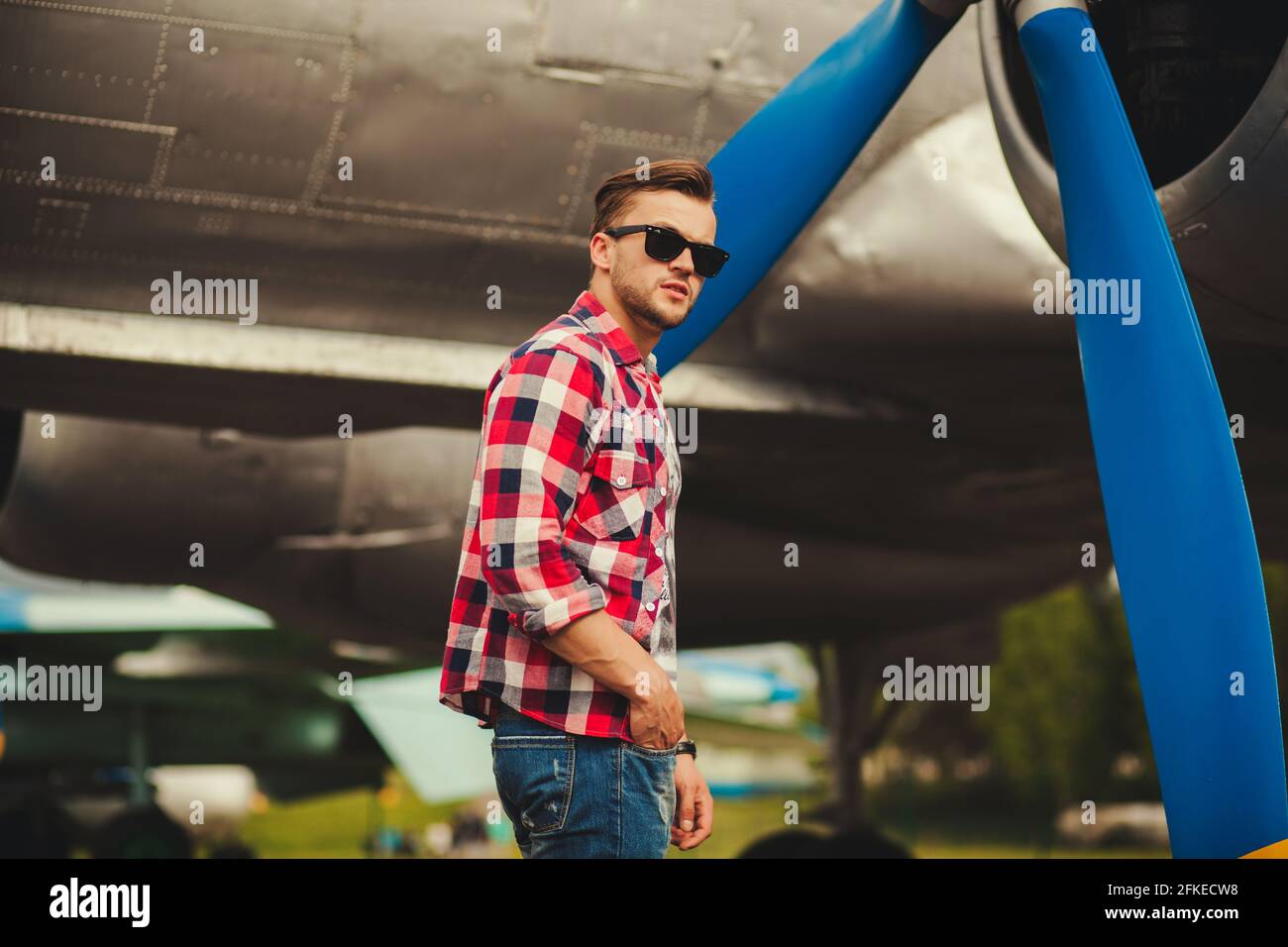 Homme modèle avec des lunettes regardant l'appareil photo sur un arrière-plan d'un avion Banque D'Images