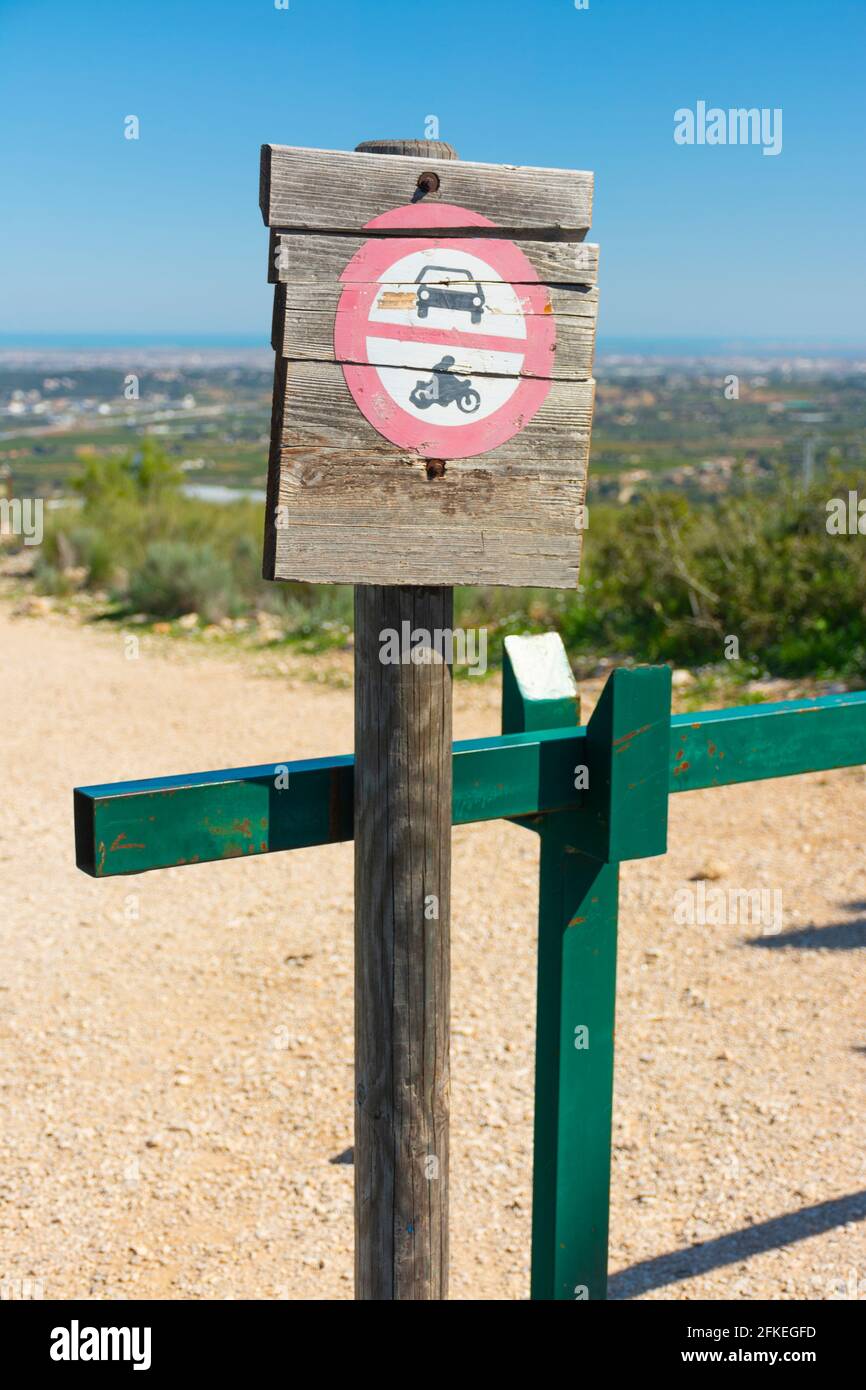 Panneau interdisant le passage de véhicules automobiles peints sur un panneau en bois, à côté d'une barrière métallique verte, dans la nature Banque D'Images