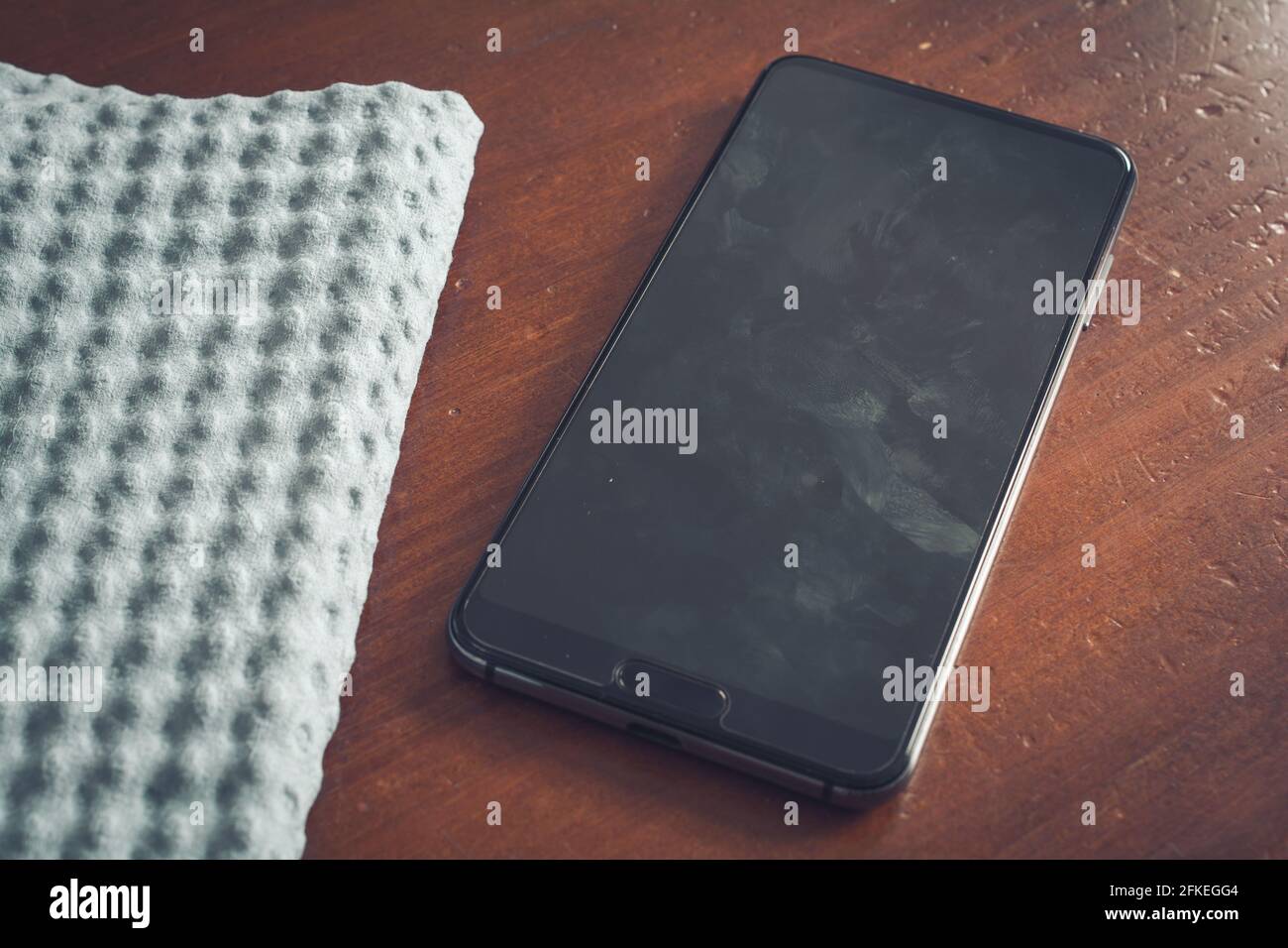 Nettoyage essuyez l'écran d'un smartphone avec de la poussière, de la saleté et des traces de doigts sur UNE table Banque D'Images