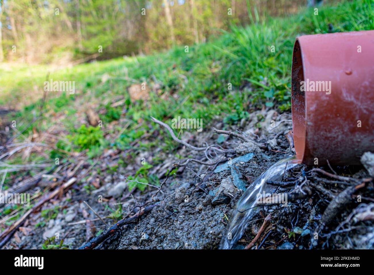 Eau pure s'écoulant dans un drain du tuyau en plastique sur arrière-plan prénal Banque D'Images