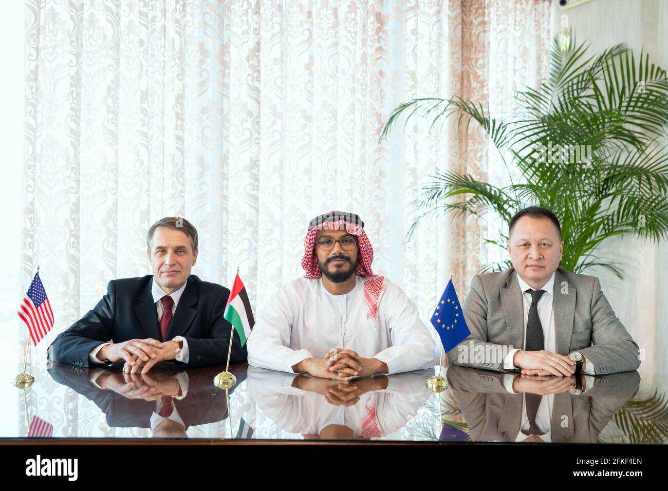 Un groupe d’hommes d’affaires interculturels confiants en tenue de cérémonie ligne par table Banque D'Images
