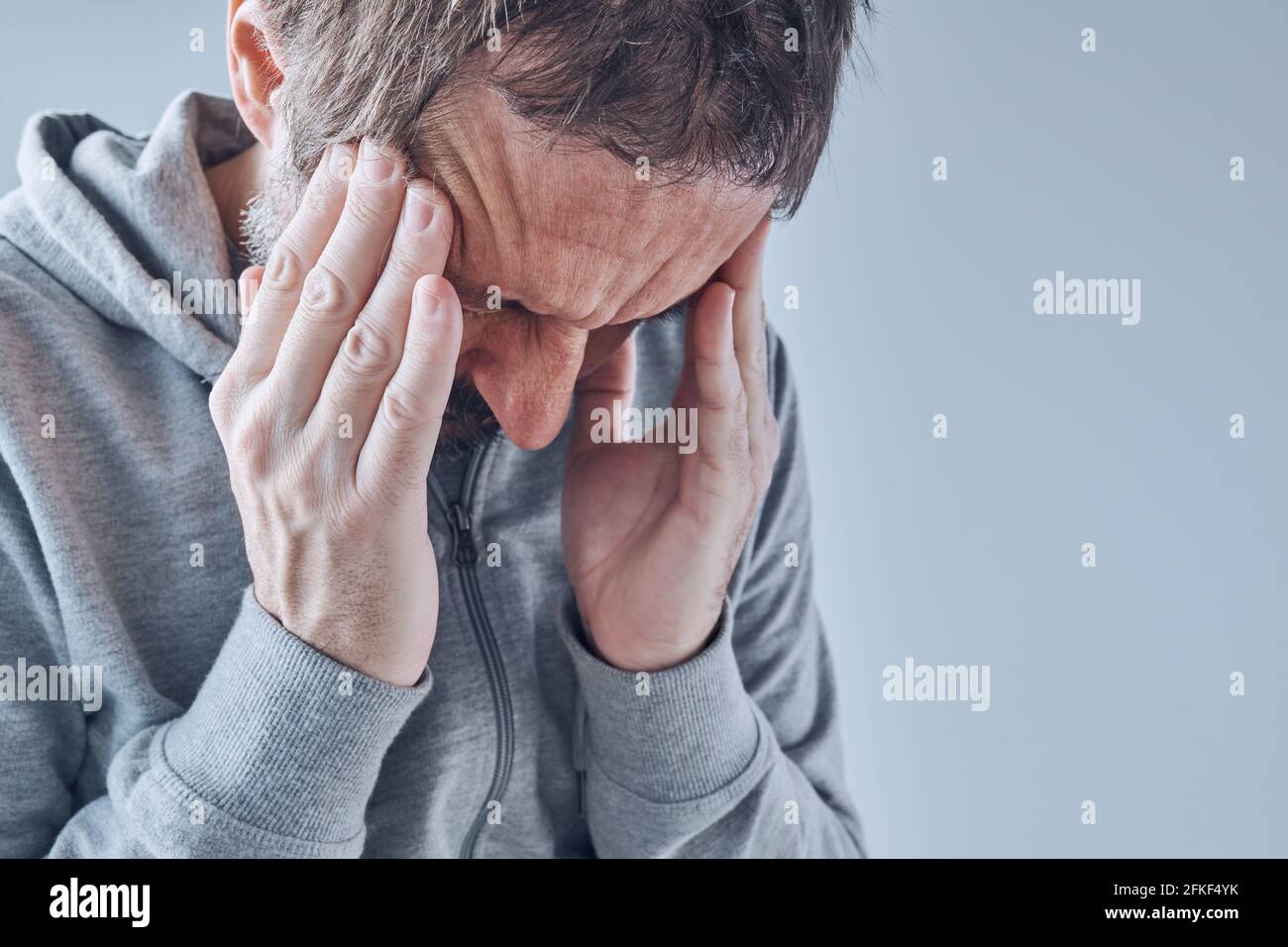 Homme caucasien adulte avec maux de tête de tension sévère, expression faciale douloureuse Banque D'Images