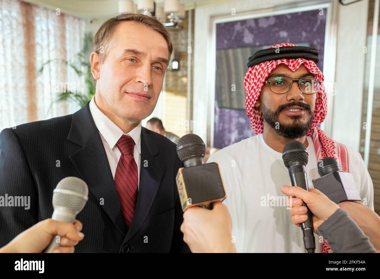 Hommes d'affaires debout devant des journalistes avec des microphones pendant l'entrevue Banque D'Images