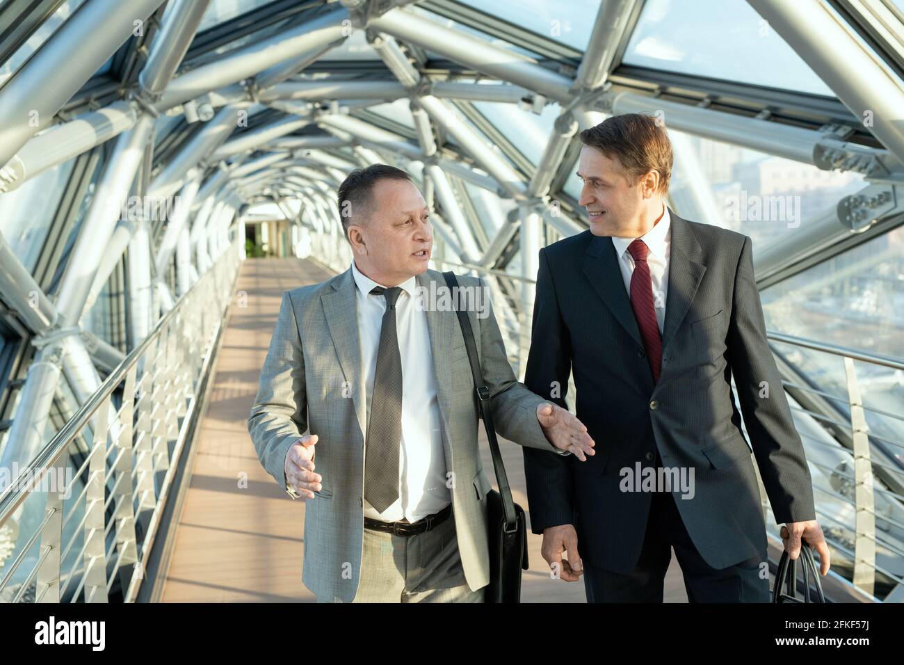 Deux hommes d'affaires confiants en costume marchant le long de bâtiment moderne Banque D'Images