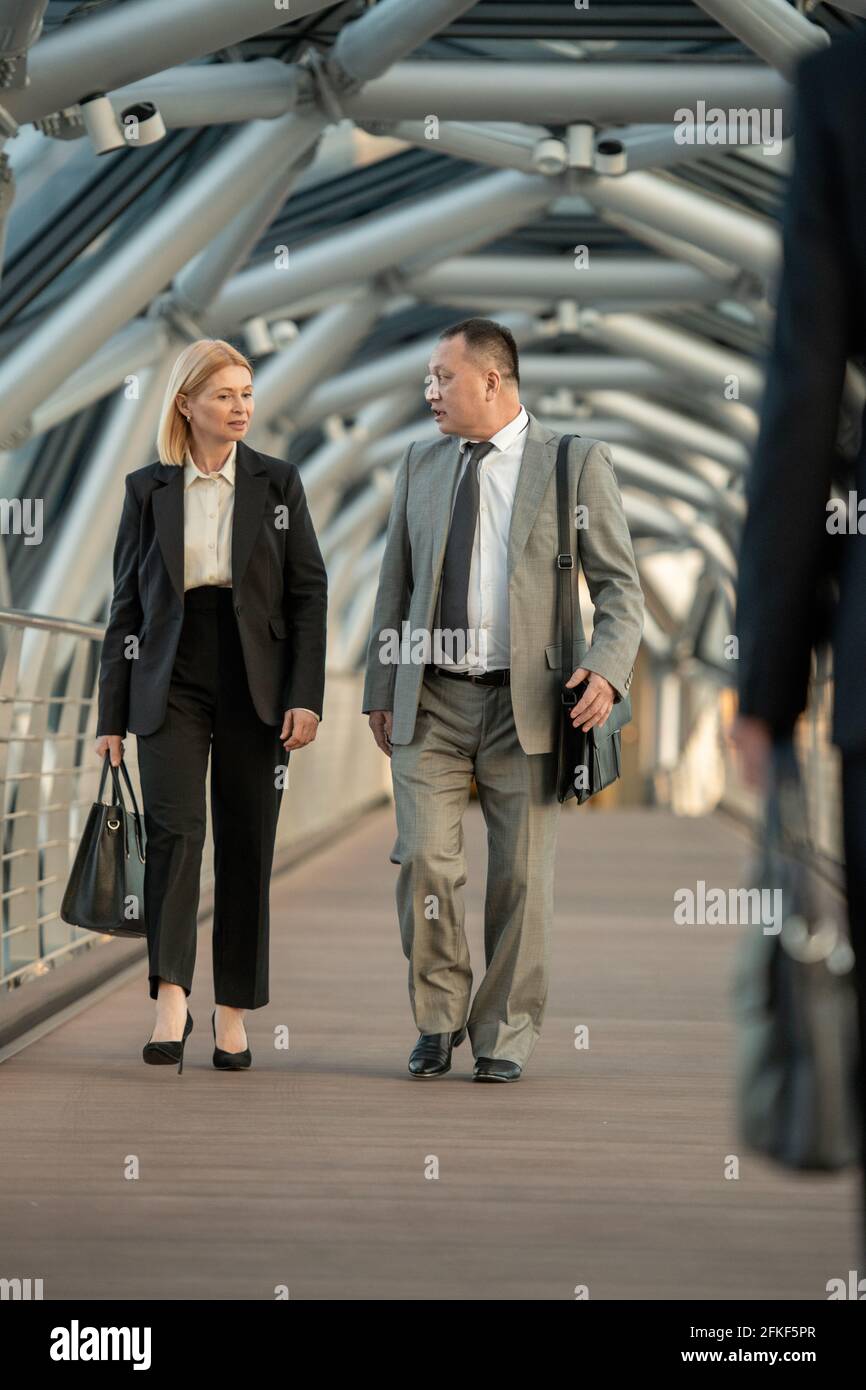 Un homme et une femme en tenue de cérémonie discutant des termes du contrat en déplacement Banque D'Images