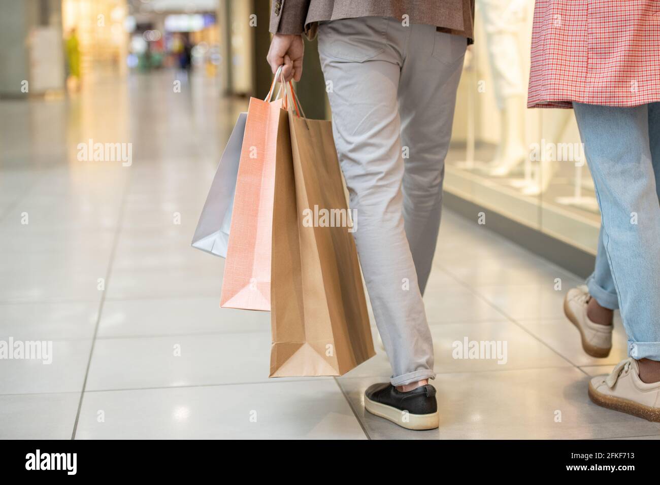 Homme portant des sacs de shopping tout en se déplaçant à l'intérieur du centre commercial Banque D'Images