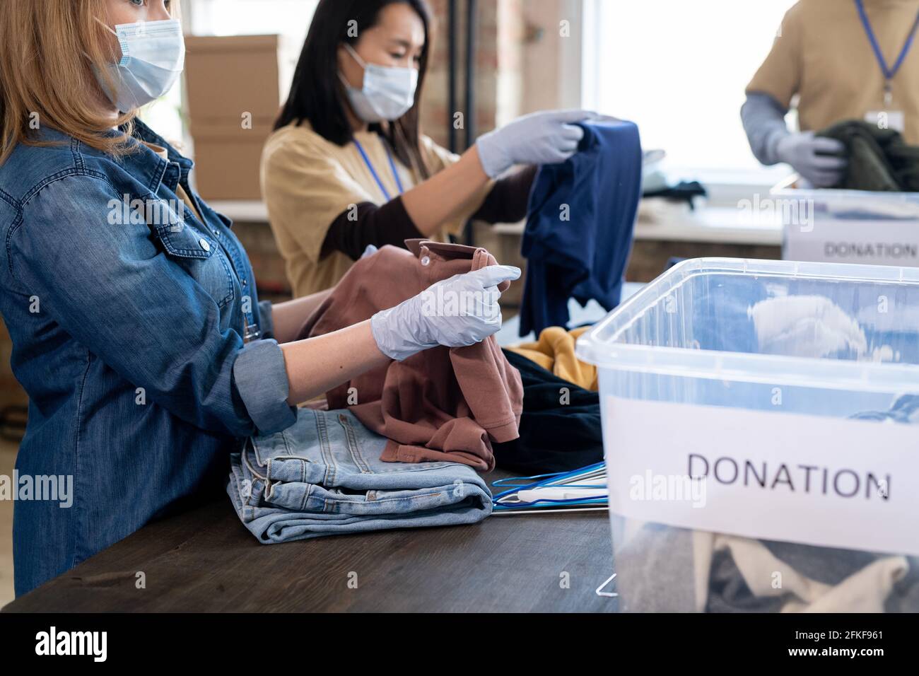 Jeune femme en gants et masque dépliante t-shirt sur la table Banque D'Images