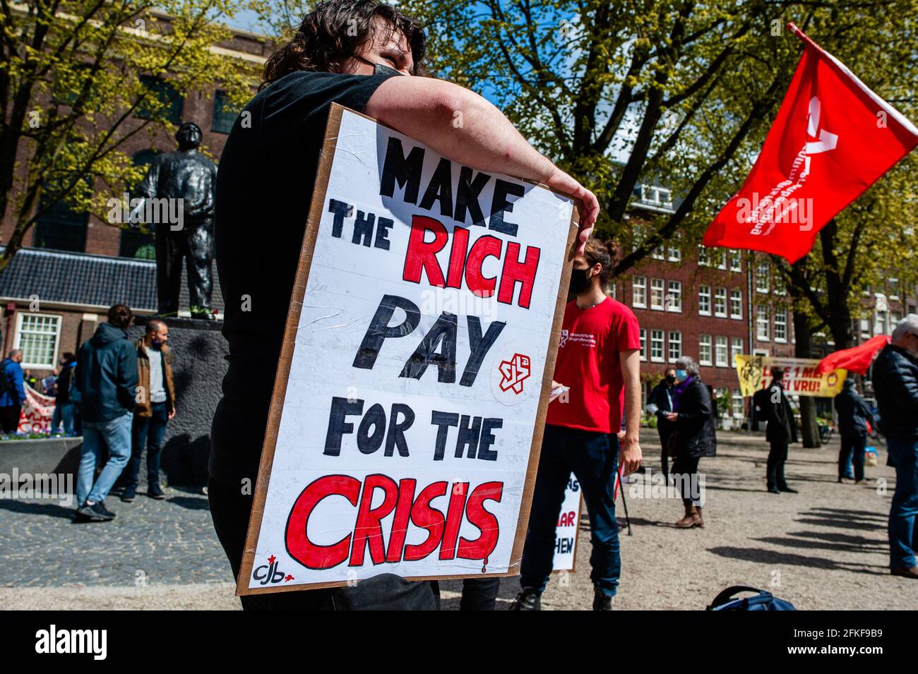 Amsterdam, pays-Bas. 1er mai 2021. Un manifestant tient un écriteau contre les riches pendant la manifestation.le jour de la Journée internationale du travail, également connue sous le nom de Fête du travail, à Amsterdam, les gens se sont rassemblés sur la place Jonas Daniël Meijer pour exiger des conditions de travail équitables telles qu'un salaire minimum de 14 euros par heure, des contrats permanents, un bon logement social, un bon système de retraite, un accès gratuit à des soins de santé complets (mentaux) et une éducation gratuite. Crédit : SOPA Images Limited/Alamy Live News Banque D'Images