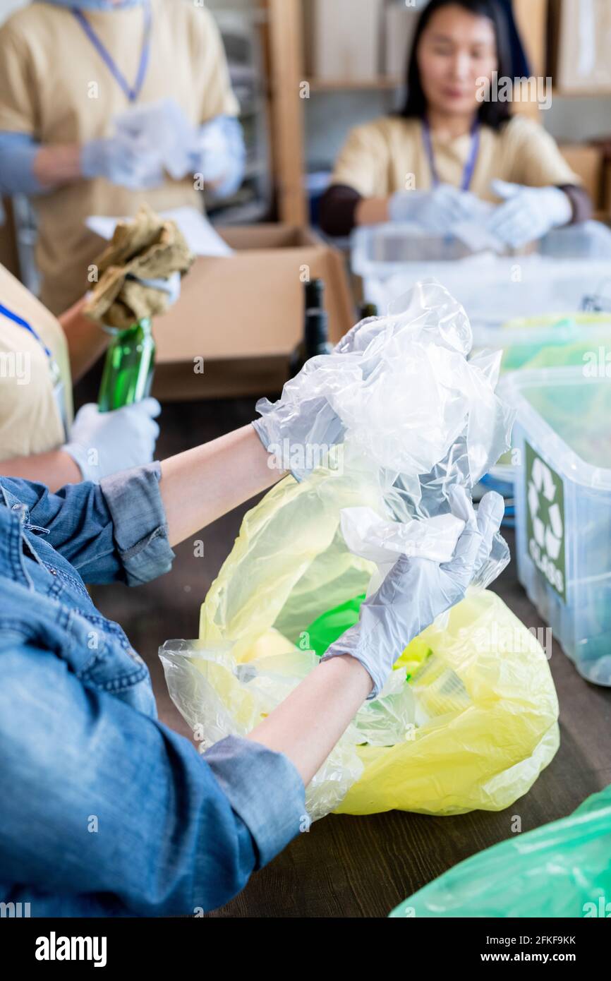 Des bénévoles gantés travaillant sur de grandes tables tout en recyclant les déchets Banque D'Images