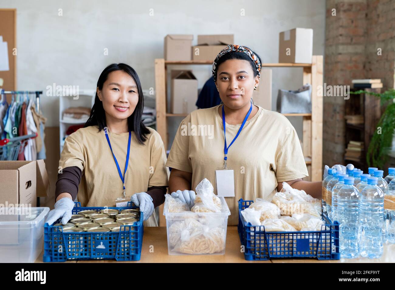 Deux jeunes femmes bénévoles debout à table avec de la nourriture gratuite dans des boîtes en plastique Banque D'Images