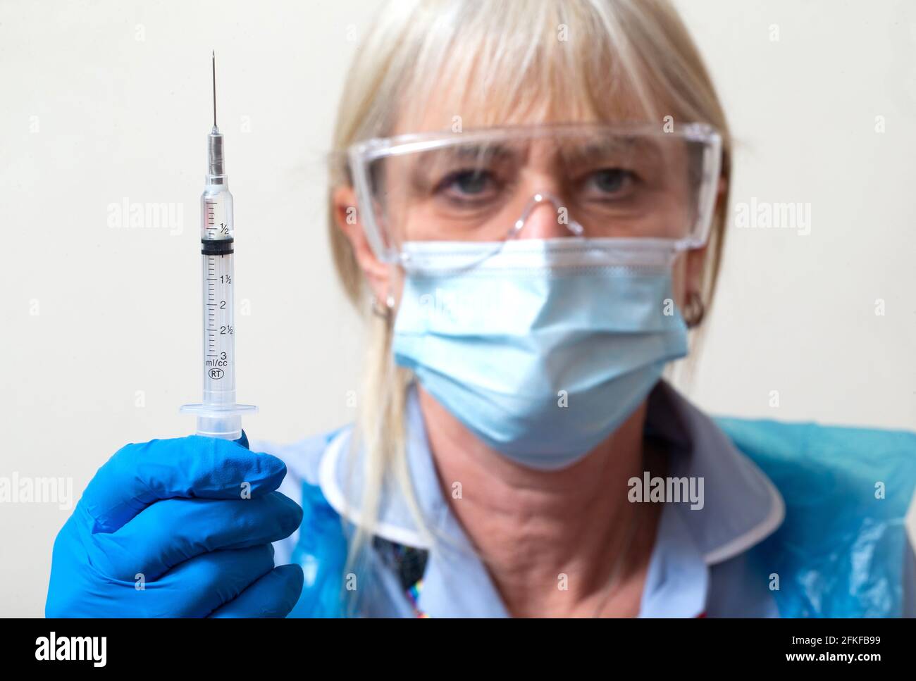 Une infirmière du NHS vérifie une aiguille avec une dose du vaccin Covid.elle administrera ensuite le premier vaccin. Banque D'Images